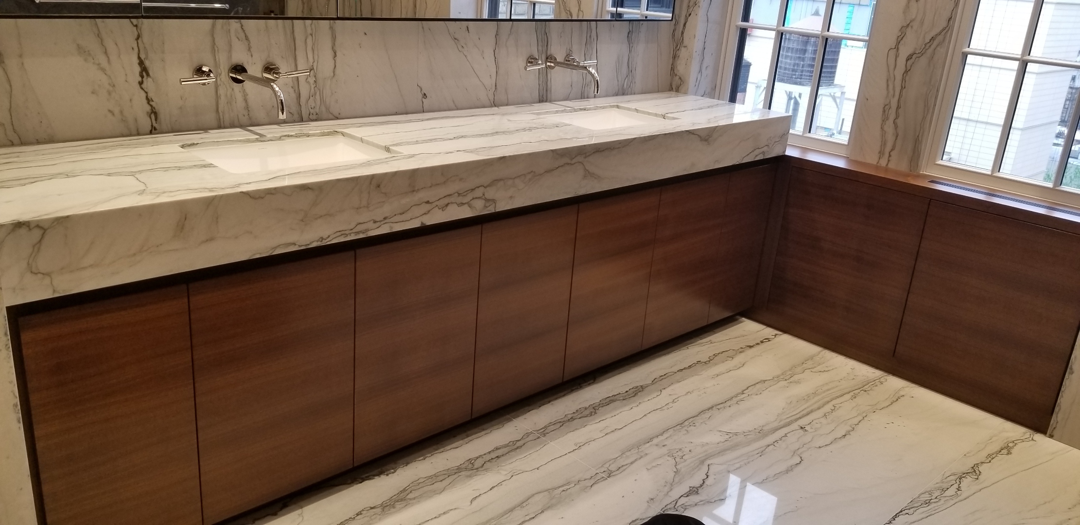 Custom bathroom double vanity in Manhattan NYC, reeded white oak drawer faces, monolithic bookmatched quartzite countertop with ramp sinks